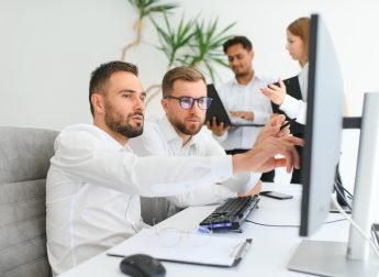 Team of brokers is working in office using workstation and analysis technology.